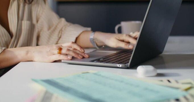 A woman opens her laptop while starting work in the office. Close-up of her hands, unrecognizable person