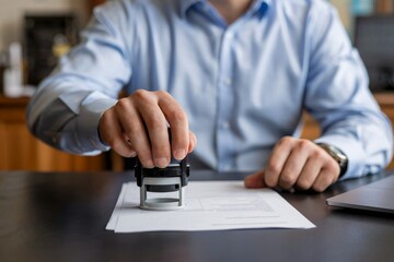 Close-up of a businessman's hand stamping a document on a desk, concept for business, corporate, and legal processes