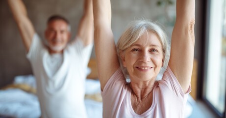Senior couple stretching arms in bedroom. Healthy lifestyle, wellness, wellbeing, flexibility, morning exercise, senior living, retirement goals.