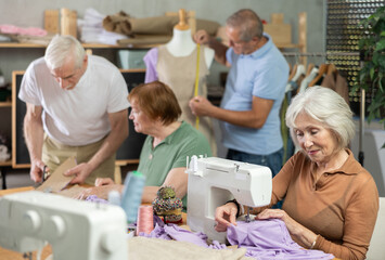 Obraz premium Some people talking, while others sew, work with mannequin, cut out dress pattern. Senior people while away time among like-minded people