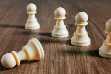 Chessmen standing with one chess pawn lying