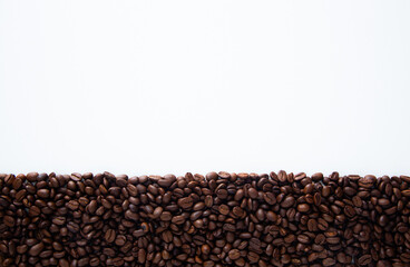 Roasted coffee beans creating bottom border on white background