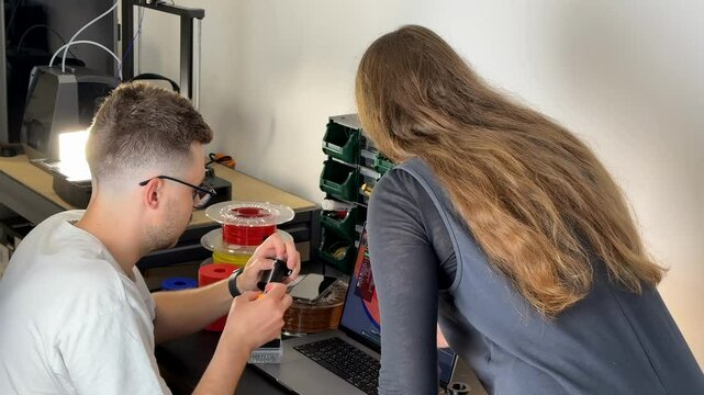 Young Caucasian male and female engineers collaborate in a workshop, focusing on electronics and prototyping
