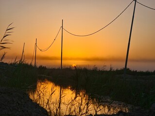 Golden sunset reflects in a calm canal, rural landscape