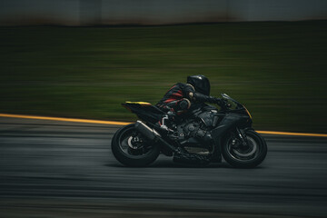 motorcycle road racer in all black on track leaned over