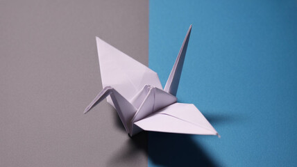 folded paper origami crane in pastel colors displayed on a flat background