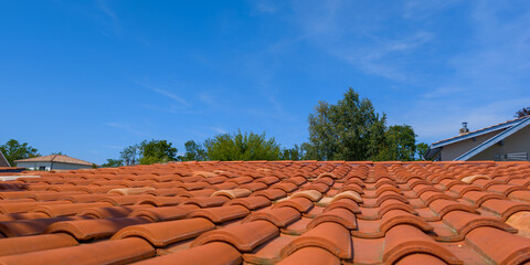 Red tiles house roof and blue sky background with tree