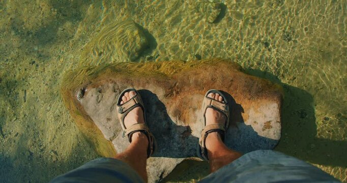 Man standing on large rock under clear shallow water of Cetina river in Croatia