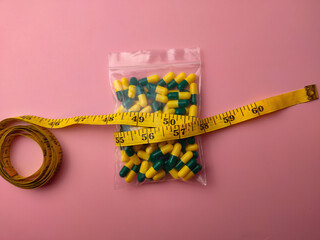 Top view of a medicine pill package with measuring tape on a pink background