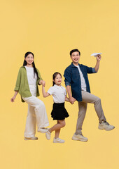 Obraz premium Joyful family of three strides forward against a yellow backdrop celebrating moments of togetherness