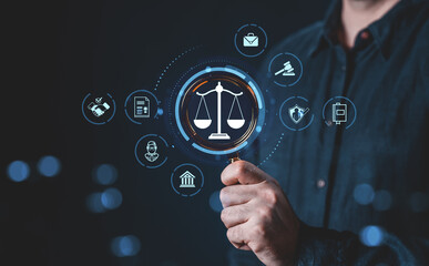 Legal system icons around magnifying glass held by hand on dark background.