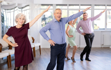 Fototapeta premium Happy senior woman and man enjoying active boogie-woogie dance in modern studio. Social dancing concept