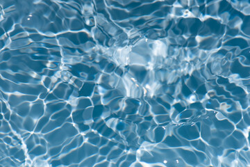 Blue water with ripples on the surface. Defocus blurred transparent blue colored clear calm water surface texture with splashes and bubbles. Water waves with shining pattern texture background.