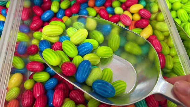 background of bright vibrant colorful jelly beans, wood spoon comes in and scoops up some candy.