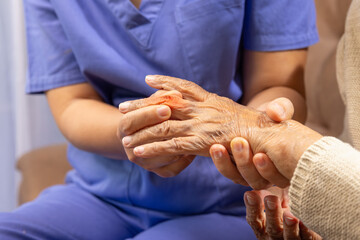 Caregiver massaging finger of elderly woman in painful swollen gout..