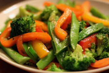 A plate of vegetables including broccoli, carrots, and green beans. The broccoli is cut into pieces and is the largest piece of the dish