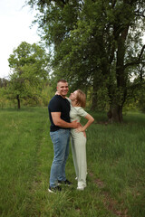Obraz premium Young couple embracing affectionately in a lush green setting Their genuine smiles and close physical connection evoke a sense of love joy and emotional intimacy ideal for romantic lifestyle content