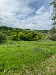 Beautiful landscapes of nature. The European part of the forest-steppe. The steep or steep slopes are densely covered with grass and trees. Above them the sky creates wonderful pictures of the sky clo