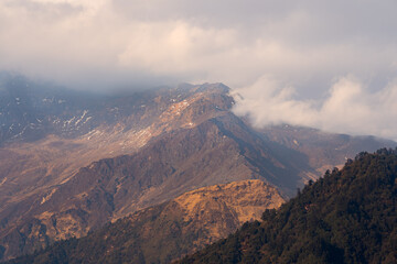 A breathtaking view of the snow-capped peaks when the clouds softly hug the mountains in great Himalayas in Nepal.