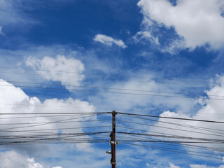Electrical pole against hazy blue sky with power lines