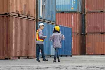 Engineer and foreman worker team in hardhat and safety vest checking containers box from cargo,...