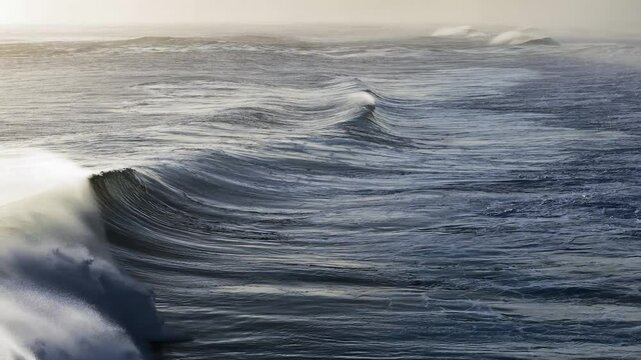 Aerial view of rolling waves crashing over a reef in slow motion. The surf creates a mesmerizing texture.