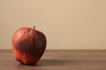 One rotten red apple on wooden table. Space for text