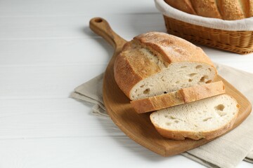 Cut bread loaf on white wooden table, closeup. Space for text