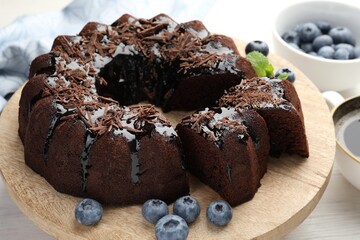 Delicious bundt cake with blueberries and chocolate shavings on light wooden table, closeup