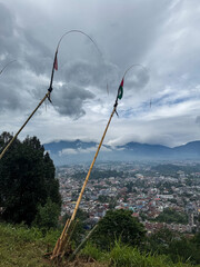 Scenic cityscape view of Cipanas, West Java, Indonesia, with bamboo poles and cloudy mountains in...