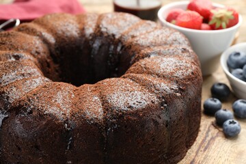 Delicious chocolate bundt cake with blueberries on wooden table, closeup