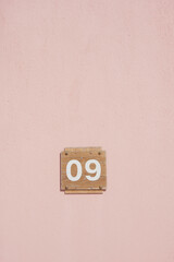 Pink wall with a wooden number sign indicating nine