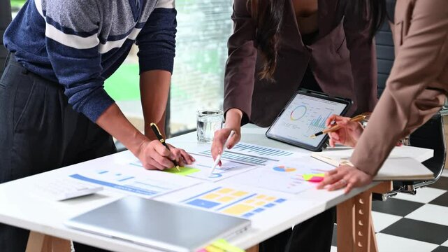 Business team analyzing data and charts in a modern office, collaborating on finance strategy