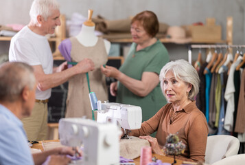 Senior couple work with mannequin at sewing school studio, mature man and woman students sew and...