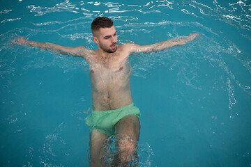 Man floating peacefully in warm spa water with eyes closed and arms outstretched on the edge of the pool.