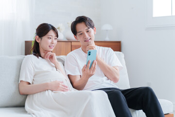 スマホを見る妊婦の妻と夫