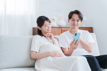 スマホを見る妊婦の妻と夫