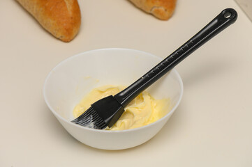 A block of creamy butter with a pastry brush, ready for baking or cooking, placed on a clean white...