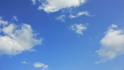 Obraz premium A peaceful daytime scene of a vibrant blue sky filled with wispy and fluffy white clouds, representing tranquility and clear weather