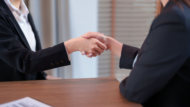 Business Handshake Between Two Asian Women Adults at Office Desk Successful Partnership Collaboration Agreement Meeting Professional Corporate Deal