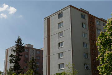Contemporary multistory apartment buildings are located amidst beautiful trees and under clear, bright skies