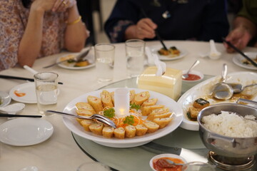 A serving of heavy Chinese food in the form of roulade and rice and other side dishes with a glass of drink such as tea and water on a round table for guests at an event at a restaurant