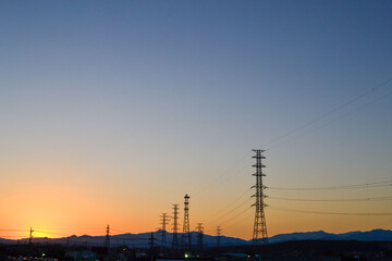 Fototapeta premium Expansive Blue and Orange Gradient Sunset Sky Over Silhouetted Mountains and Power Lines