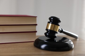 Judge's gavel and books on wooden table indoors, closeup