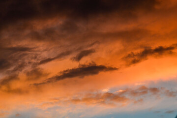 Obraz premium Intense Orange and Dark Gray Clouds Creating a Burning Sky Effect at Sunset