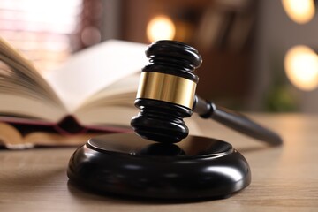 Judge's gavel and book on wooden table indoors, selective focus