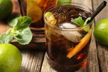Refreshing Cuba libre cocktail with mint on wooden table, closeup
