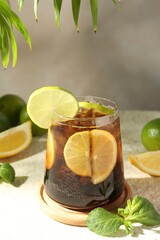 Fototapeta premium Tasty Cuba Libre cocktail in glass and ingredients on light textured table