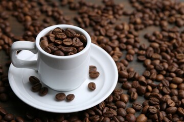 Aromatic coffee beans, cup and saucer on table, closeup. Space for text