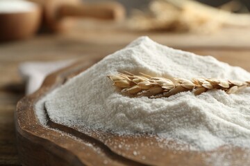Wheat flour and spikelet on wooden table, closeup